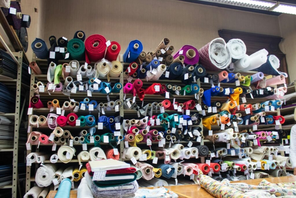 A vibrant display of diverse fabric rolls stacked on shop shelves indoors.